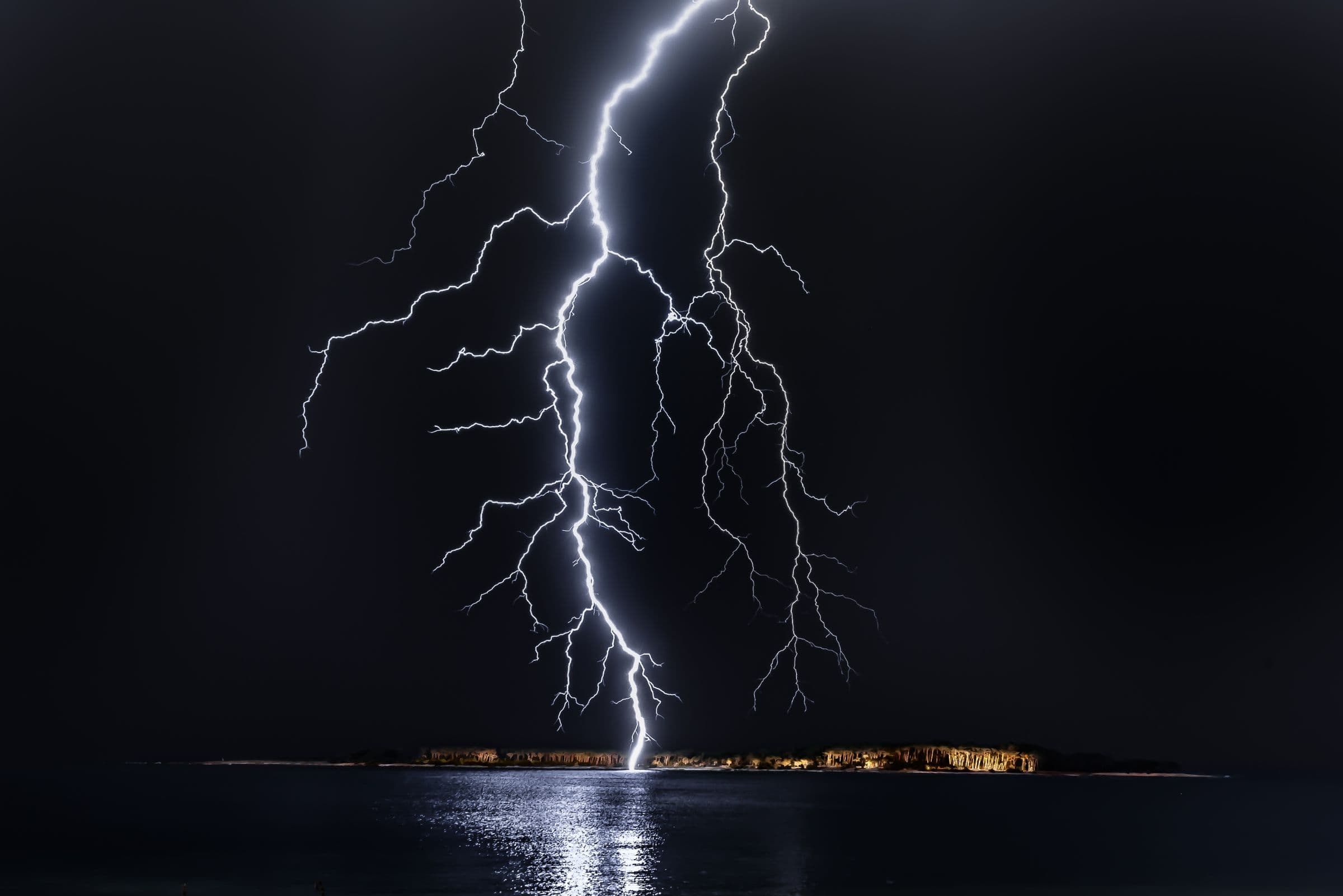 A lightning bolt striking the sea at night