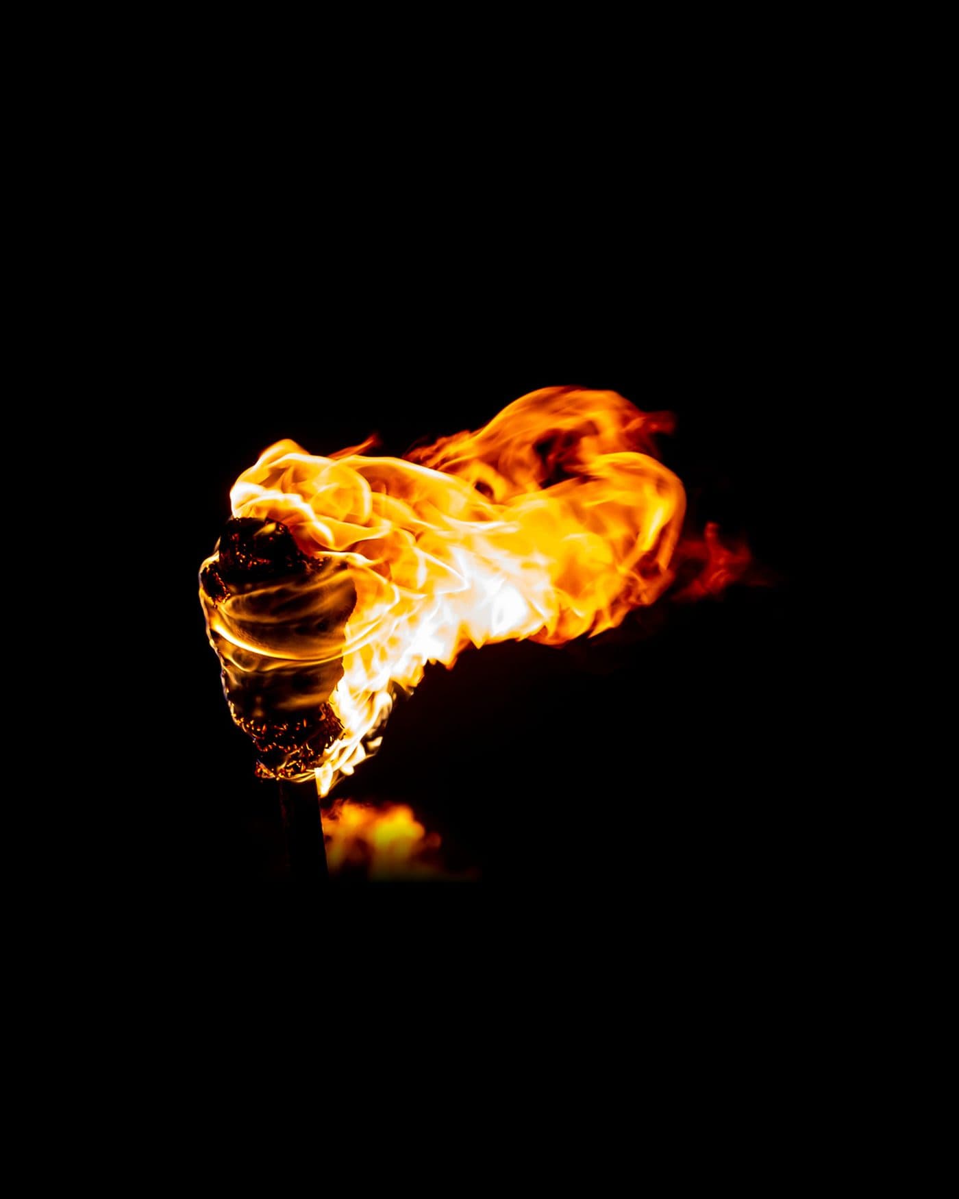 A burning torch held up against total darkness