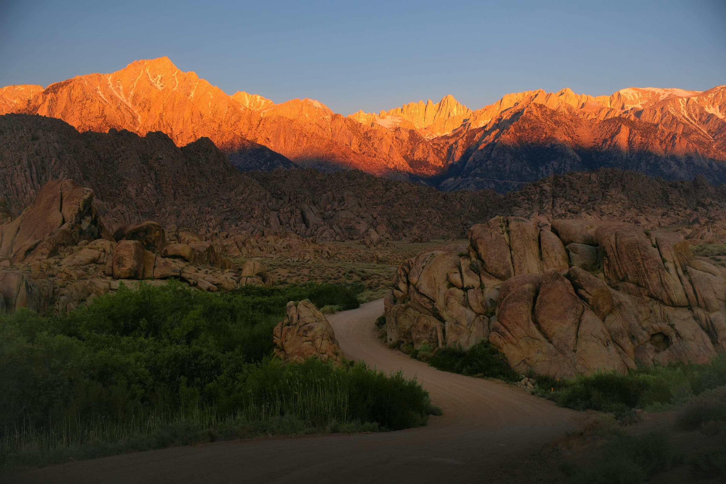 First light on a mountain range, with a road running in toward it.
